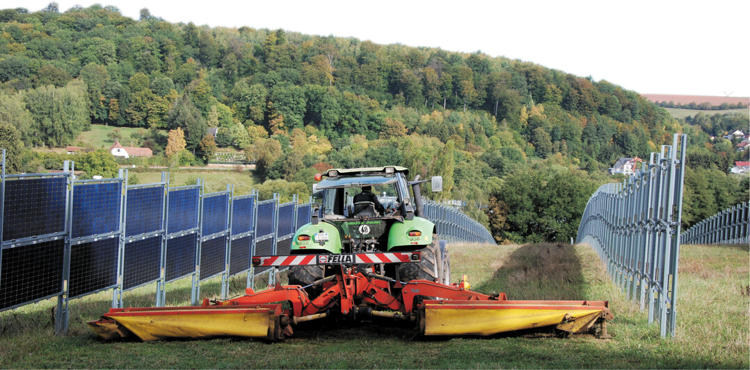 Mäharbeiten zwischen senkrecht aufgestellten Agri-Fotovoltaikanlagen.
