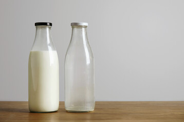 Volle und leere Milchflasche auf hlzerner Oberflche stehend.
