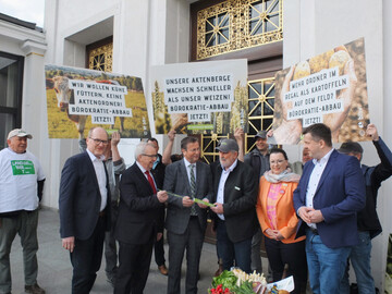 bergabe des Zollstocks (v. l.): Hans-Benno Wichert, Vizeprsident im Landesbauernverband Baden-Wrttemberg; Till Backhaus, Agrarminister Mecklenburg-Vorpommern; Peter Hauk, Landwirtschaftsminister Baden-Wrttemberg; Bernhard Bolkart, Prsident im Badischen Landwirtschaftlichen Hauptverband; Christiane Wangler, Prsidentin LandFrauenverband Sdbaden und Sven Schulze, Landwirtschaftsminister Sachsen-Anhalt, umrahmt von protestierenden Landwirten.