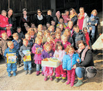 Kinder des Kindergartens Pusteblume in Tiefenbach zeigen beim Besuch auf dem Milchviehbetrieb von Sina Mack freudig ihre neue Bücherkiste.