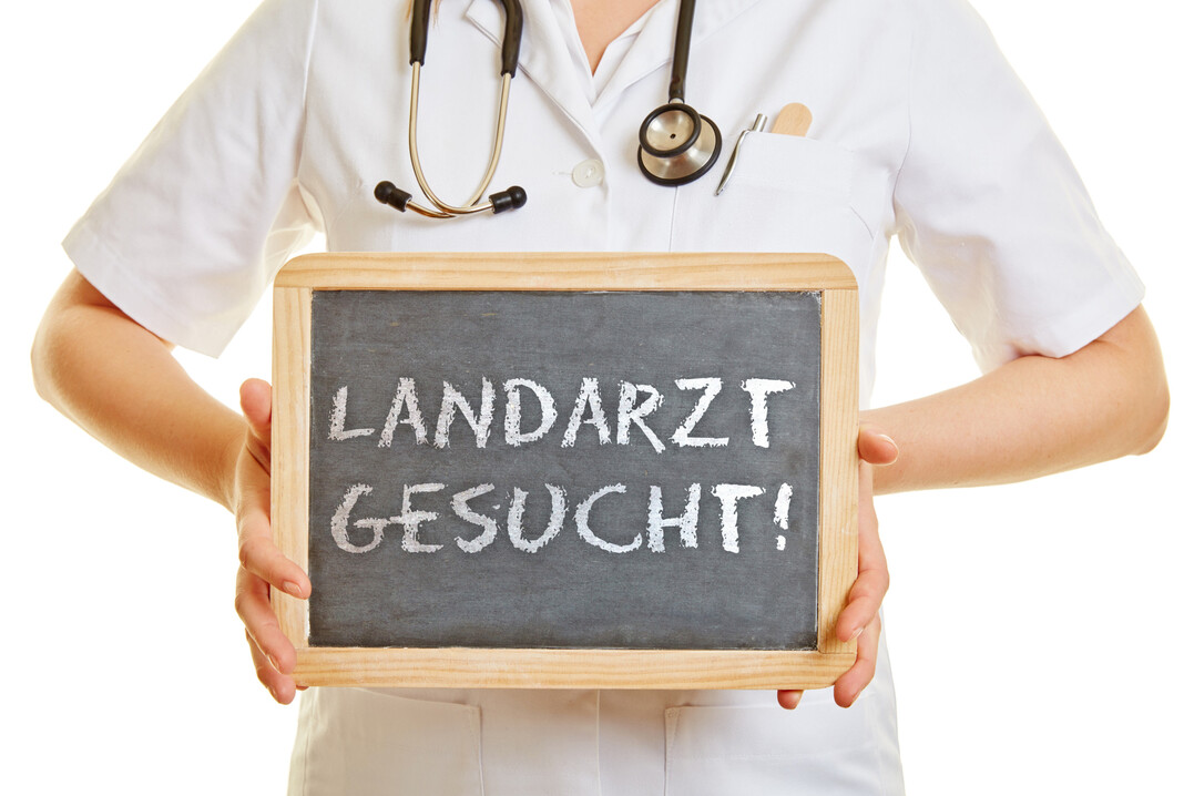 Arzt hlt ein Schild mit der Schrift "Landarzt gesucht!"