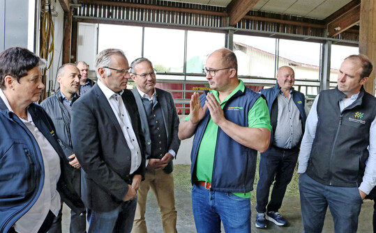 Wie moderne Milchviehhaltung mit Roboter in einem luftigen Stall und angepasst an hohe Tierwohlstandards funktioniert, erläuterte Betriebsleiter Markus Dorn-Bohner beim Rundgang. Aufmerksame Zuhörer waren unter anderen die Abgeordneten Norbert Lins, MdEP, (3. v. l.) und Raimund Haser, MdL (4. v. l.). Nach 30 Jahren Melkstanderfahrung hat sich die Familie Dorn-Bohner vor rund drei Jahren für einen Stallanbau mit zwei Melkrobotern von DeLaval entschieden. Neben den Milchkühen gibt es auf dem Hof in Hittisweiler bei Bad Waldsee eine Milchtankstelle und eine fünfzehn Jahre alte Biogasanlage mit knapp 500 kW. Zudem gehört der Betrieb zum Netzwerk Lernort Bauernhof.