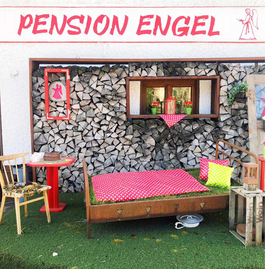 Pension Engel Zeit fr ein Nickerchen? Lust knnte so mancher Autofahrer, der durch das verschlafene Albdorf Wippingen bei Blaustein fhrt, darauf sofort bekommen. Denn diese Einladung ist doch wirklich unwiderstehlich. Die Inhaber dieser Pension setzen auf ganz andere Art von Werbung: Auf ein echtes Bett mit getupfter Bettdecke, Herzchen im Holzrahmen und sogar einem Nachttopf darunter. Auerdem gibt es viele blhende Blumen und einen kleinen Tisch mit Stuhl, auf dem ein leckerer Schokoladen-Guglhupf wartet. Die Szenerie steht auf einem Podest mit Kunstrasen. Ob man sich da kurz reinlegen darf? Isabella Hafner