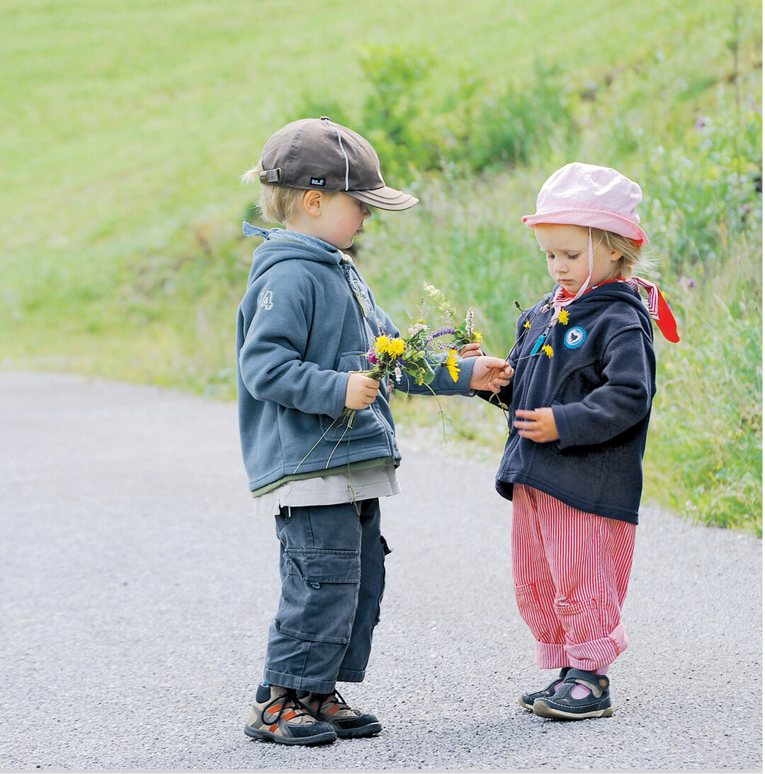 Malte und Josefine haben Wiesenblumen gepflückt. Und da Josefine noch ein gelbes Blümchen im Strauß fehlt, bekommt sie eines von ihrem Bruder überreicht.