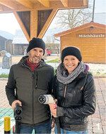 Tobias und Claudia Dreher an der Ladestation, im Milchhäusle im Hintergrund können die Stromkunden während der Ladezeit Milchprodukte und Kaffee bekommen.