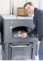 Roland Mayer demonstriert die einfache Handhabung des neuen Häussler-Holzbackofens mit Pelletbrenner.