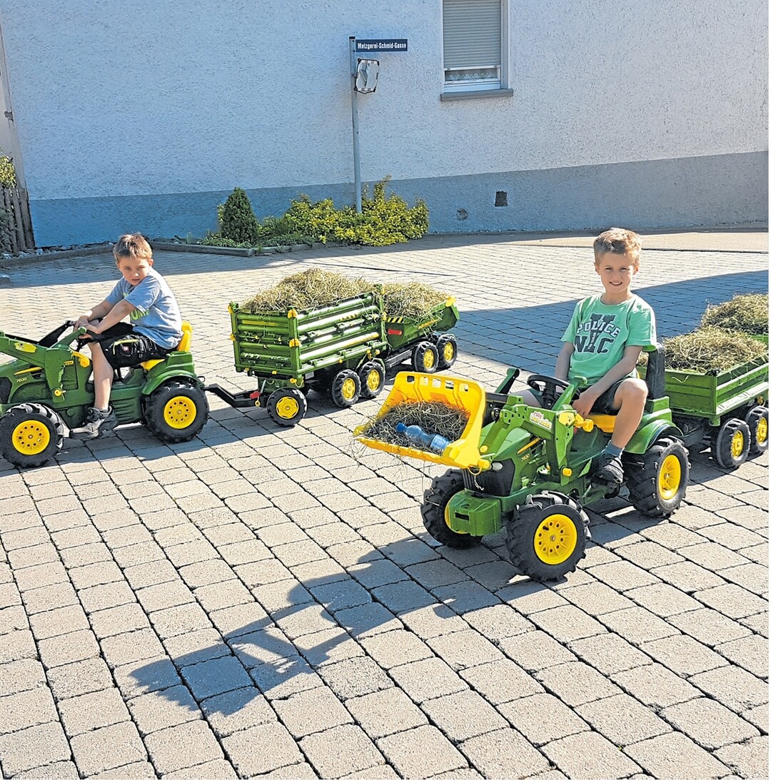 Zwei fleißige Helfer, die beiden siebenjährigen Freunde Leon (links) und Lukas, fahren in Sontheim ein paar Ladungen Heu zum benachbarten Bauern, um es an die Kühe zu verfüttern. Damit sie unterwegs gut bei Kräften bleiben, darf die Wasserreserve nicht fehlen.