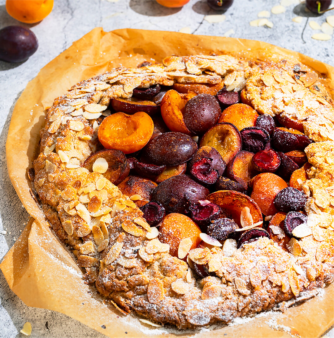 Galettes mit Steinobst 300 g Buchweizenmehl 200 g kalte Butter 1 Prise Salz 6 EL Rohrzucker 2 EL kaltes Wasser 150 g Aprikosen 150 g Pflaumen 200 g Kirschen ½ TL Zimt 1 Ei 2 EL Mandelblättchen 1 TL Puderzucker Zubereitung Für den Teig Mehl mit 3 EL Zucker, gewürfelter Butter, Salz und Wasser rasch zu einem glatten Teig kneten. Teig zu einer Kugel formen und abgedeckt für 45 Min. kaltstellen. Backofen auf 180°C (Ober-Unterhitze) vorheizen. Währenddessen Früchte waschen, entkernen und halbieren. In einer Schüssel mit dem restlichen Zucker und Zimt vermengen. Teig auf einem mit Backpapier belegten Blech ½ cm dick ausrollen. Früchte draufgeben und einen 5 cm breiten Rand lassen. Den Rand rundherum über die Früchte klappen, mit verquirltem Ei bestreichen und mit Mandelblättchen bestreuen. Galette im Ofen auf mittlerer Schiene für etwa 45 Min. (je nach Backofen) goldbraun backen. Galette abdecken, falls sie zu schnell bräunt. Aus dem Ofen nehmen, kurz auskühlen lassen, mit Puderzucker bestreuen und lauwarm genießen. Dazu passt Vanilleeis mit frisch geschlagener Sahne. BVEO