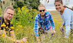 Jürgen Maurer kontrolliert zusammen mit Lisa Diehl (2. v. l.) von der Stiftung Kulturlandschaft Rheinland-Pfalz und Liesa Schnee von der Uni Göttingen die Entwicklung von Insekten und deren Larven in seiner Blühfläche bei Feßbach.