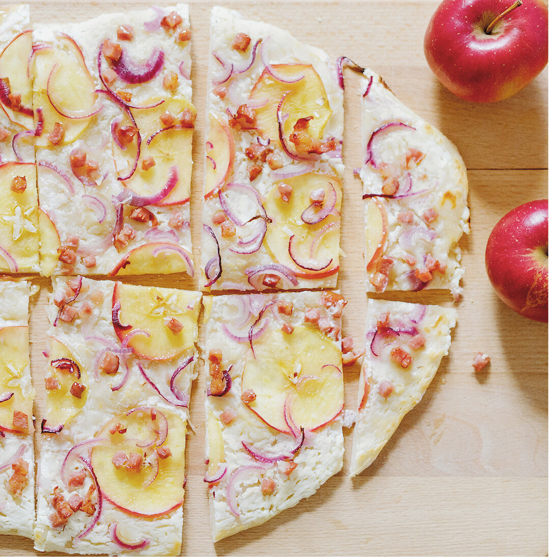 Dieser leckere Apfelflammkuchen ist schnell zubereitet. Der Boden aus dünnem Hefeteig wird mit 200 Gramm Schmand bestrichen, mit Speckwürfeln, dünn gehobelten Apfelscheiben und Zwiebelringen belegt, mit Salz und Pfeffer etwas gewürzt. Bei 250 Grad im unteren Ofendrittel knapp 15 Minuten backen. Zum Schluss zwei Esslöffel flüssigen Honig über den Flammkuchen träufeln.
