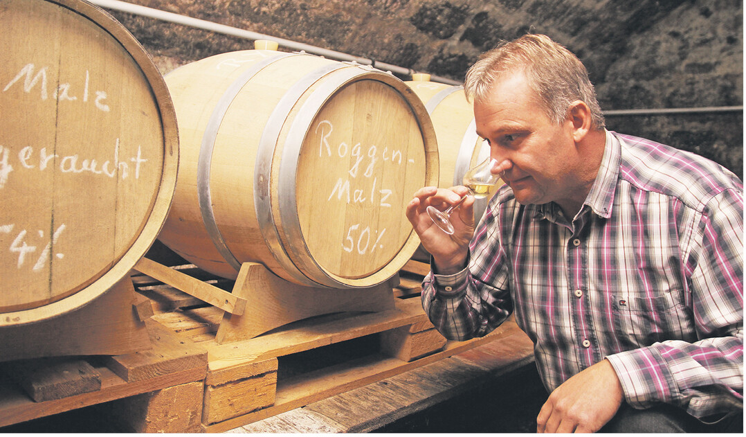 Jungwhiskyprobe – Karl Müller schnuppert an einem torfgerauchten Gerstenbrand aus eigener Herstellung. Die Getreidebrände reifen seit knapp drei Jahren im Gewölbekeller.