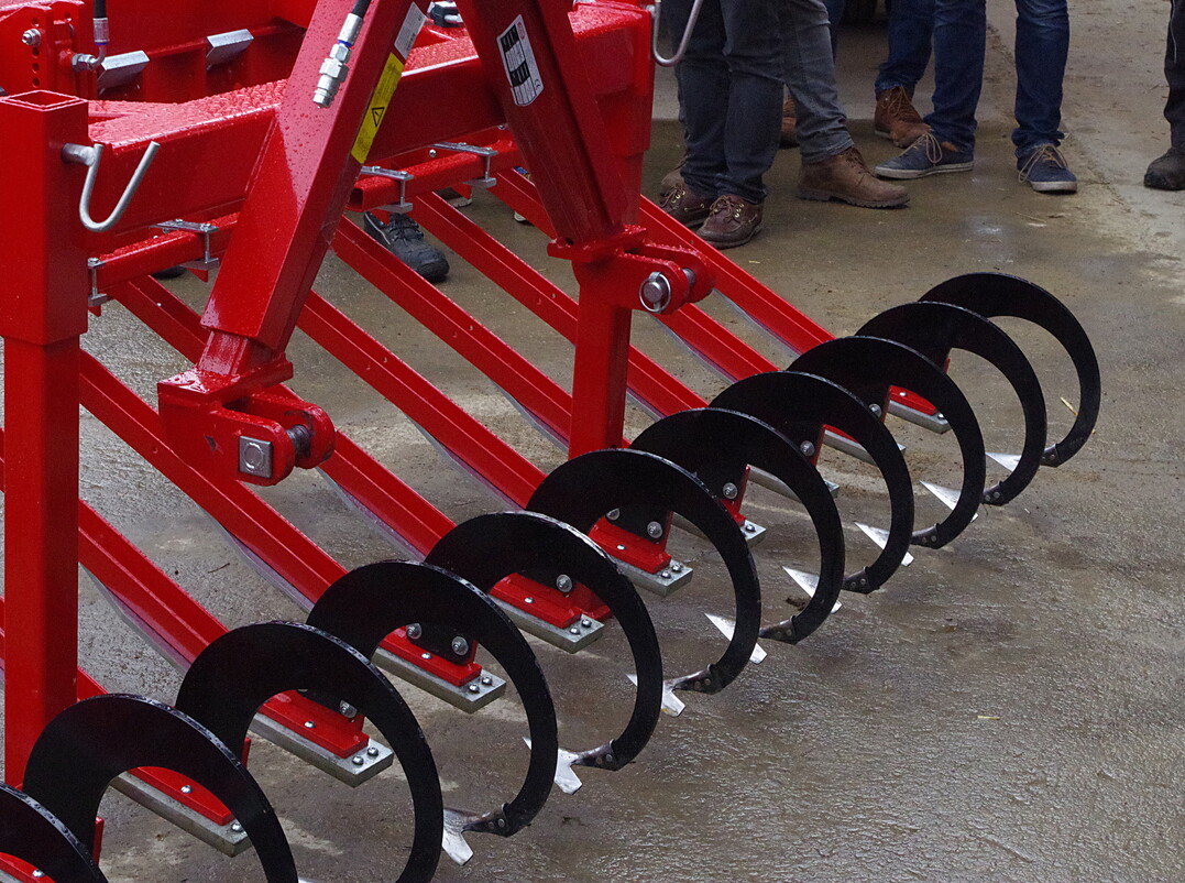 Hacke Maschinenbau Dieter Leibing: Ein Modell mit sechs Metern Arbeitsbreite war an der Fronthydraulik im Feldeinsatz. Über eine Druckfeder und eine Gleitkufe soll sich das Hackschar an den Boden anpassen. Bei der Demonstration betrug die Bearbeitungstiefe an der Scharspitze etwa 2,5 Zentimeter und ein Zentimeter an der Flanke der Schar. Der Hersteller fertigt nach eigenen Angaben auf Kundenwunsch individuell.