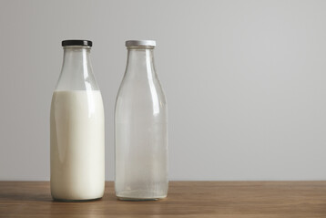 Volle und leere Milchflasche auf hlzerner Oberflche stehend