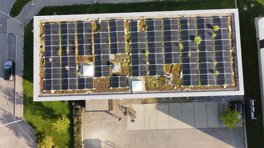 Luftbild mit Blick auf das Flachdach mit den aufgestnderten PV-Modulen.