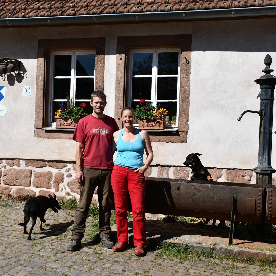 Die Betriebsleiter Nina und Sebastian Kill mit ihren Hunden vor dem Hofladen.