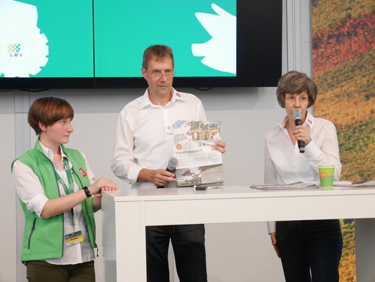 "Glserne Redaktion" prsentiert Ihre Aktivitten auf der Bhne in Halle 1 (von links): Juniorreporterin Elisa Igersheim, Technik-Fachredakteur und Chef vom Dienst Michael Neub, Fachredakteurin Gudrun Koeck.