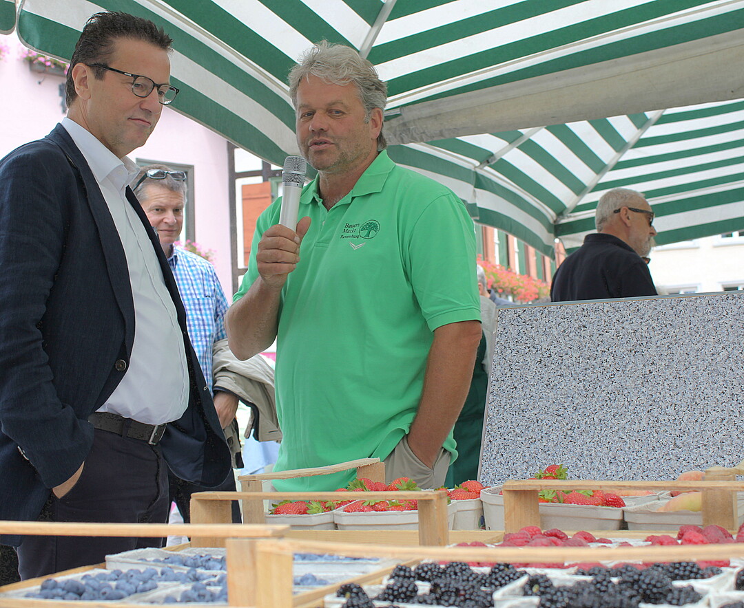 Am Stand des Bauernmarktes Ravensburg informiert sich der Minister bei Thomas Heilig, im Vorstand der Bauernmarkthalle, ber Obst vom Bodensee.