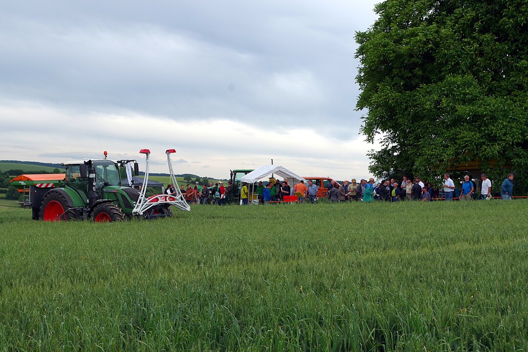 Bei einem Festzelt fanden sich die rund 120 Teilnehmer zum Beginn des Getreidetags am Zentralen Versuchsfeld ein. Im Vordergrund steht ein Traktor mit Dngerstreuer und Pflanzensensor.