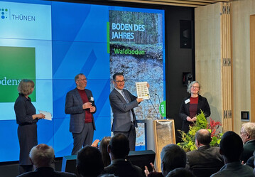 Bundesminister Cem zdemir prsentiert die aktuelle Sonderbriefmarke zum Waldboden als Boden des Jahres.