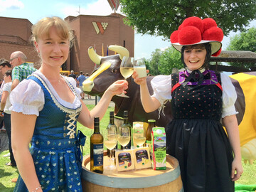 Ein Muuh und ein zum Wohl - Ehemalige Badische Weinknigin Isabella Vetter und Schwarzwaldmilch-Mitarbeiterin Jasmin Mbius in Schwarzwald-Tracht stoen vor Sonnenwinzer-Kuh und der Belegschaft der Schwarzwaldmilch und dem Badischen Winzerkeller auf Besuch in Breisach an.