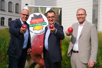 Jörg Hilbers (l.), Geschäftsführer Fachgruppe Obstbau, Cem Özdemir, Bundesminister für Ernährung und Landwirtschaft, Dr. Christian Weseloh (r.), Geschäftsführer Bundesvereinigung der Erzeugerorganisationen Obst und Gemüse werben für heimische Äpfel.